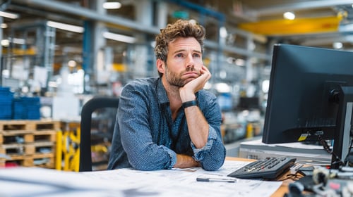 Een oudere man met grijs haar geeft een uitleg aan een jongere man aan een computer
